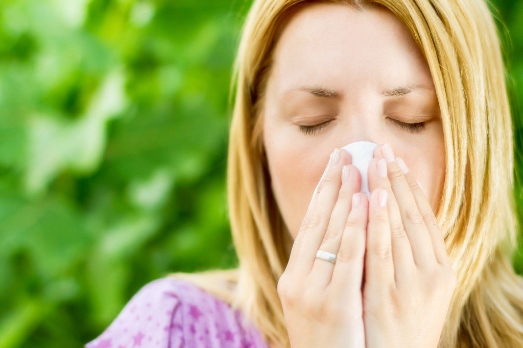 Allergy Medicine - Woman blowing her nose outside